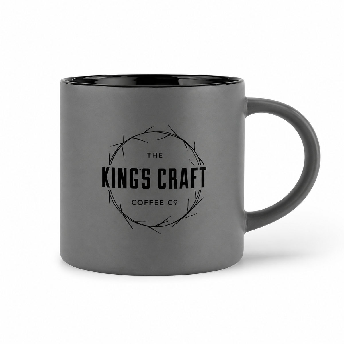 A dark gray ceramic coffee mug with a black interior and handle, featuring a black printed logo for 'The King's Craft Coffee Co' in the center, set against a plain white background.