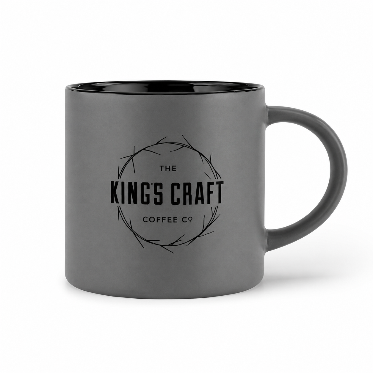 A dark gray ceramic coffee mug with a black interior and handle, featuring a black printed logo for 'The King's Craft Coffee Co' in the center, set against a plain white background.